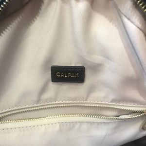 Calpak “Kaya” in black with gold zippers.